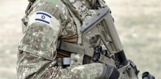Soldier in camouflage gear with Israeli flag patch.