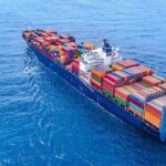 Cargo ship carrying colorful containers in open sea.