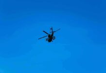 Silhouette of a helicopter against clear blue sky.