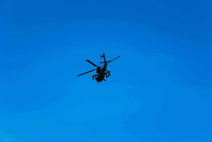 Silhouette of a helicopter against clear blue sky.