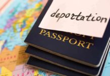 pile of passports with the word deportation written on a sticky note attached to top