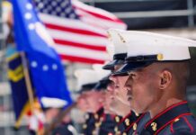 Marines in uniform standing in line, American flags displayed.