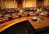 Empty courtroom with scales of justice in foreground.