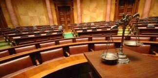 Empty courtroom with scales of justice in foreground.