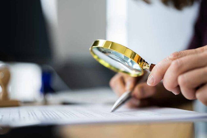 1895848177 featured image Person examining document with magnifying glass.