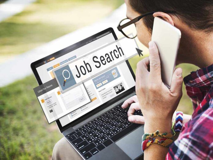 413845555 featured image Person searching job on laptop while holding phone.