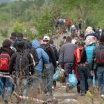 Migrants Embark On Trek To U.S. Border Amid Policy Shifts Group of people walking through rural area.