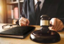 Gavel judges hand glasses and book on desk