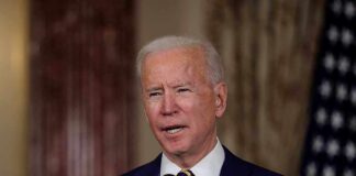 Man speaking at podium with microphones indoors