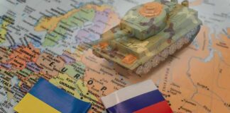 Toy tank on map with Ukraine and Russia flags