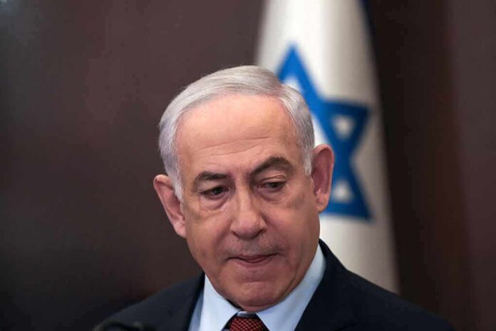 2415917203 featured image Man in suit with Israeli flag in background.