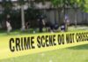 Yellow crime scene tape blocking grassy area.