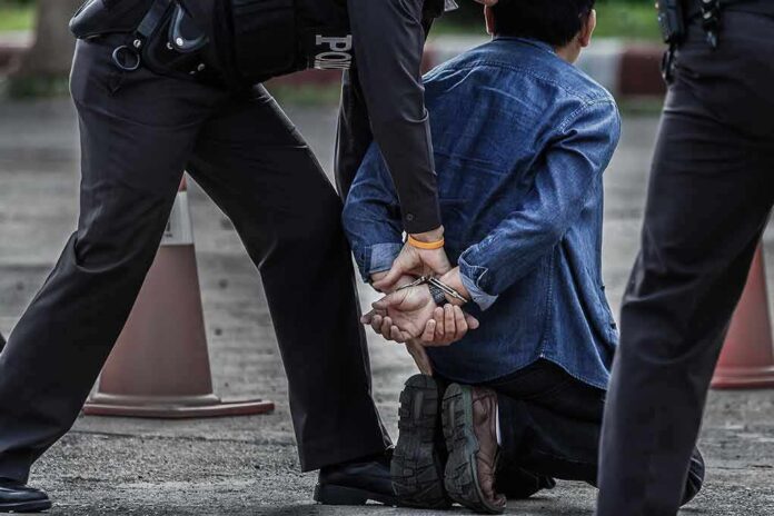 659470504 featured image Person handcuffed by police officers on street kneeling