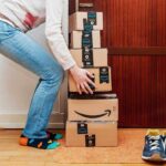 Person stacking Amazon boxes near door shoes nearby