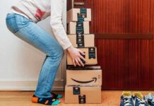 Person stacking Amazon boxes near door shoes nearby