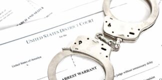 Handcuffs on top of an arrest warrant document