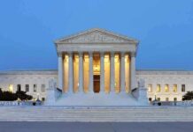 Large neoclassical building with illuminated columns at dusk