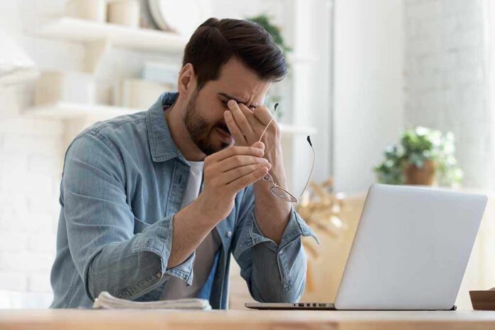 1575539137 featured image Man holding glasses, looking tired at laptop.