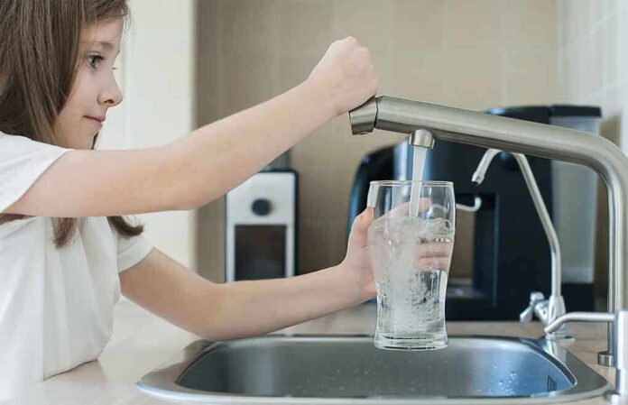 1742845301 featured image Girl filling glass with water from kitchen faucet.