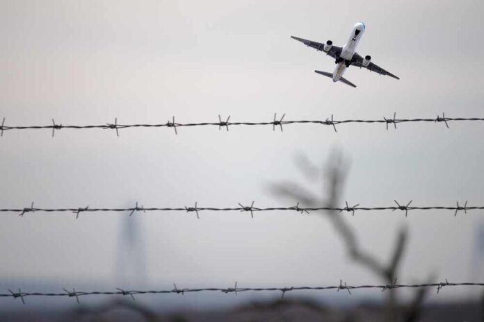 2401451327 featured image Airplane ascending above barbed wire fence sky background