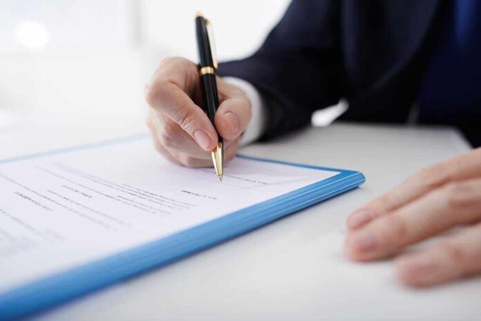 381270436 featured image Person signing a document with a black pen.