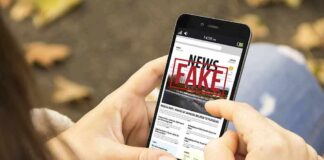 Person holding smartphone displaying fake news notification