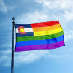 Colorful flag with rainbow stripes against blue sky