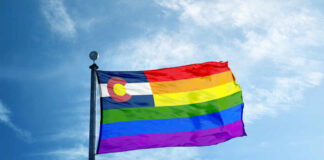 Colorful flag with rainbow stripes against blue sky