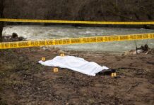 Crime scene with body near river and police tape