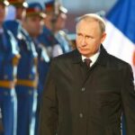A man in dark coat at a military event