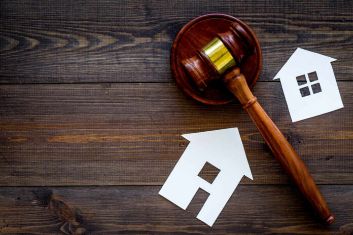 Gavel and house cutouts on wooden surface