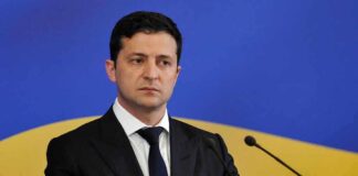 Man in suit speaking at podium with microphones