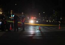 Police officers standing near caution tape at night