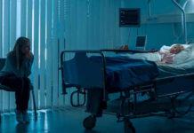 Woman sitting beside hospital bed at night