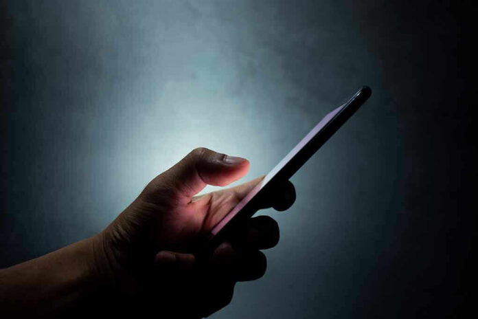 1431658976 Hand holding a smartphone in dim light