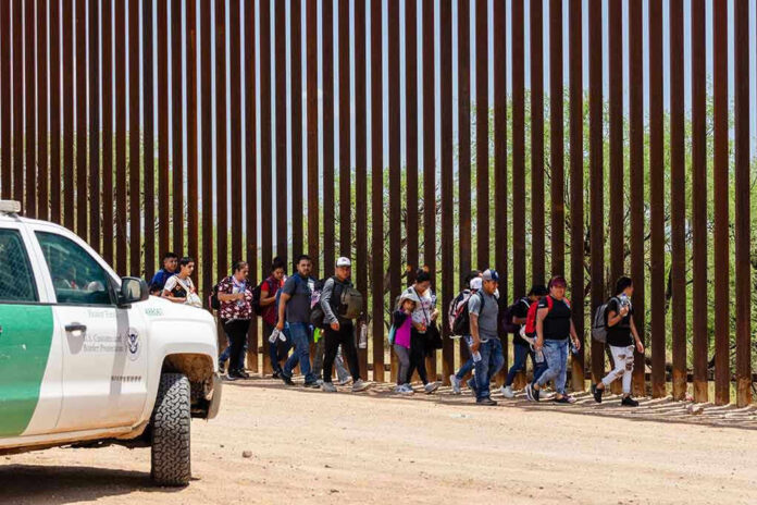2333258557 People walking beside tall fence and border patrol vehicle