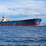 A large cargo ship sailing on the ocean under a blue sky