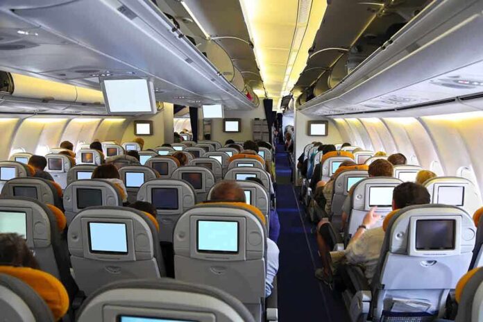 shutterstock_142431973.jpg Interior view of an airplane with passengers seated and using in flight entertainment screens