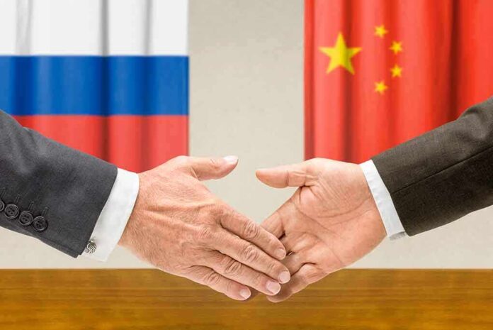 shutterstock_196161602.jpg Two hands shaking in front of Russian and Chinese flags