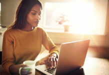 How Protein Coffee Became Everyone’s New Ritual Woman using a laptop while holding a mug