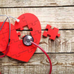 STUNNING Discovery Links Heart To Brain Decline Red heart puzzle with stethoscope on wooden background.