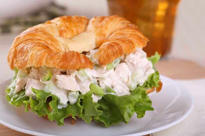 A croissant sandwich filled with chicken salad and lettuce on a plate