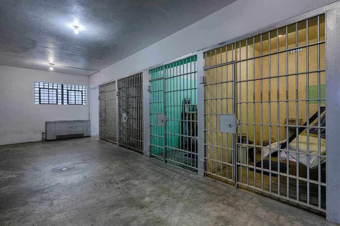 Interior view of a prison cell block with metal bars and concrete flooring