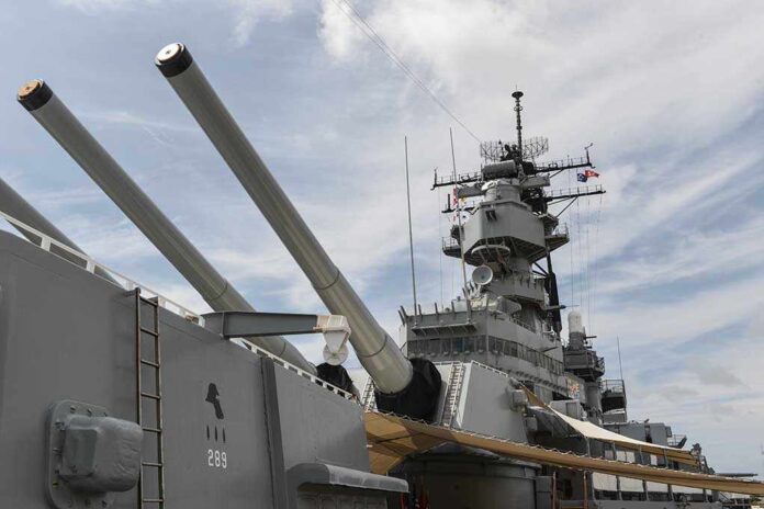 Close-up of a battleship's naval guns and superstructure against a cloudy sky