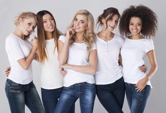 Five women in white tshirts and jeans smiling together