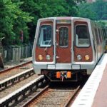 Metro train arriving at a station surrounded by greenery