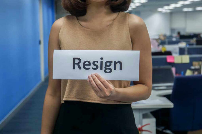 Person holding a sign that says resign