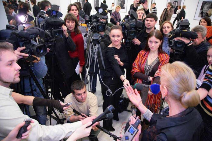 A crowded press conference with journalists and cameras surrounding a speaker