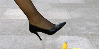 A high heel shoe poised above a banana peel on a tiled floor