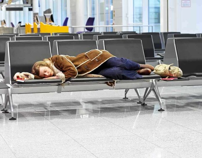 shutterstock_89998417.jpg A traveler sleeping on a bench in an airport waiting area
